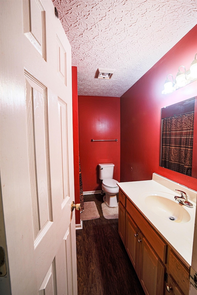 bathroom with vanity, wood-type flooring, a textured ceiling, and toilet