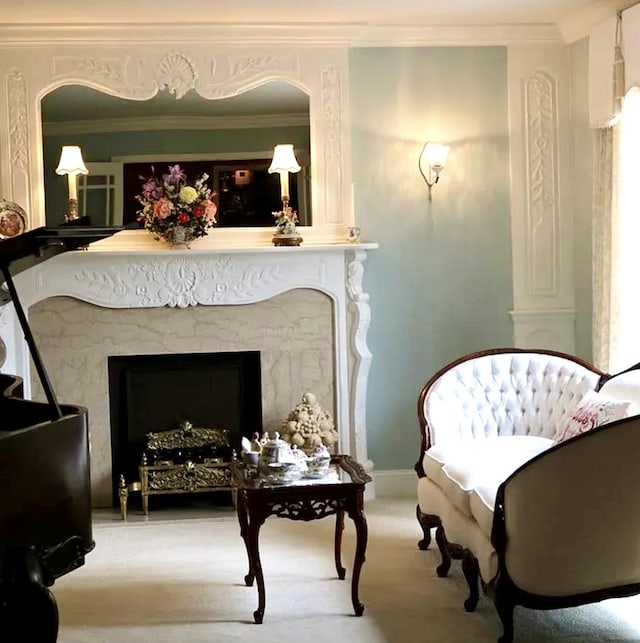 living area with carpet, a high end fireplace, and crown molding