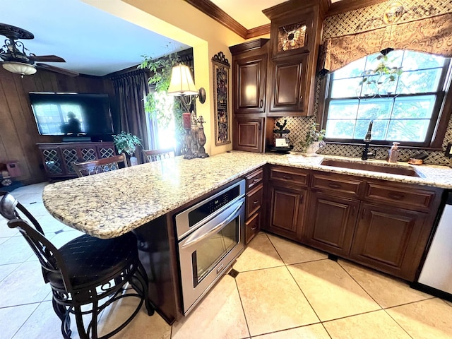 kitchen featuring decorative backsplash, dishwasher, crown molding, stainless steel oven, and a sink