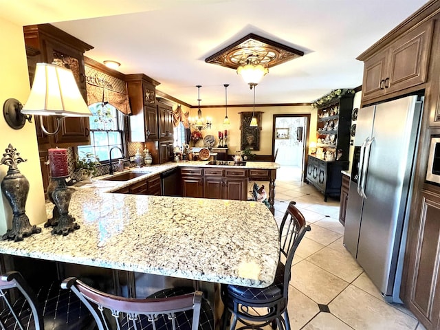 kitchen with light stone counters, a peninsula, a sink, ornamental molding, and stainless steel fridge