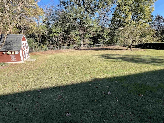 view of yard featuring an outdoor structure, fence, and a shed