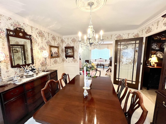 dining room with a decorative wall, a wainscoted wall, wallpapered walls, an inviting chandelier, and crown molding