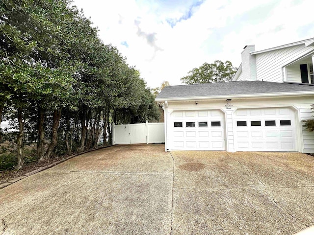 garage featuring fence and concrete driveway