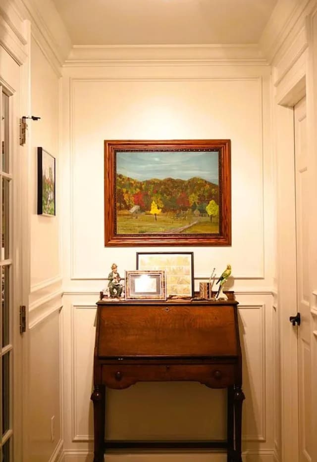 interior details featuring crown molding and a decorative wall