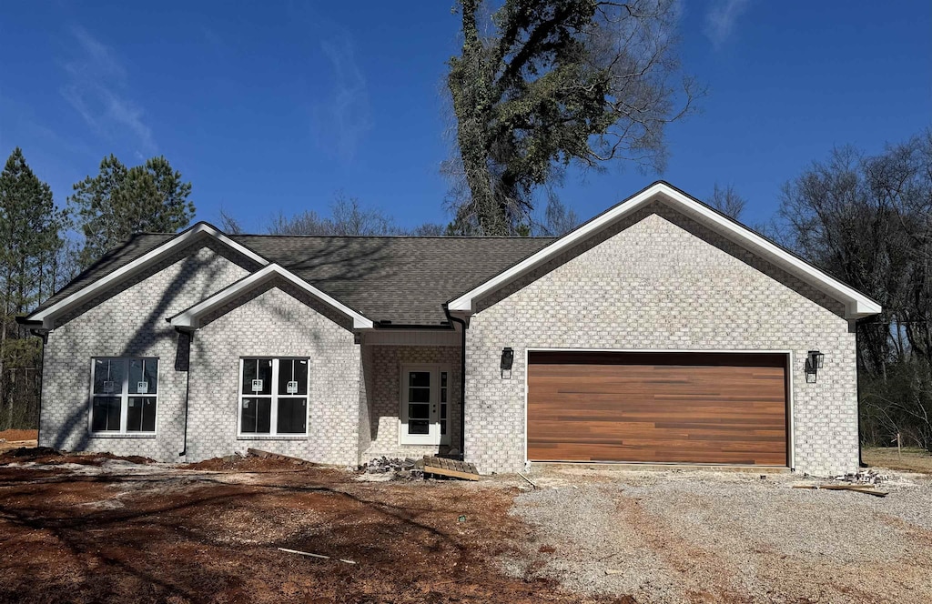 single story home featuring an attached garage, driveway, and brick siding