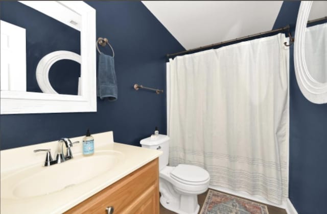 bathroom with vanity, toilet, and lofted ceiling