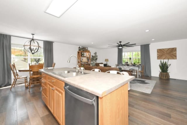 kitchen featuring sink, stainless steel dishwasher, dark hardwood / wood-style floors, decorative light fixtures, and a center island with sink