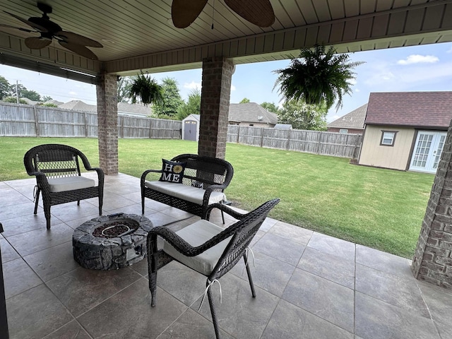  - view of patio featuring ceiling fan, an outbuilding, and a fire pit