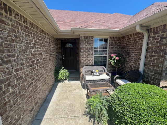  - doorway to property with roof with shingles and brick siding