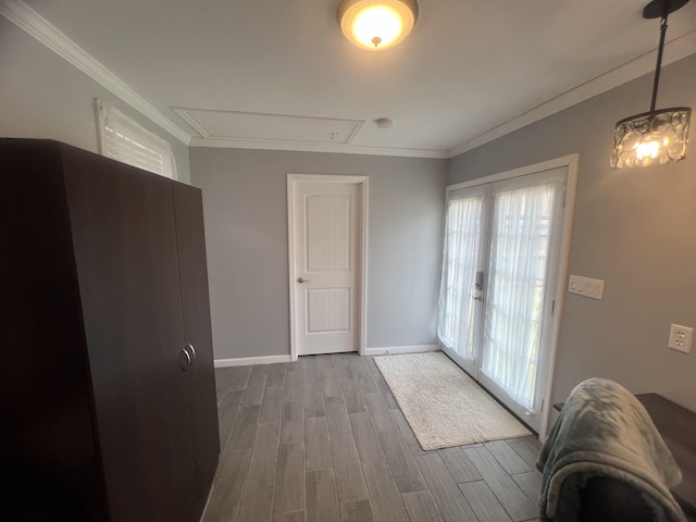  - doorway to outside with wood finished floors, crown molding, and baseboards