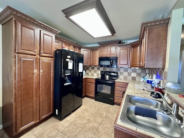 - kitchen featuring black appliances, a sink, light countertops, tasteful backsplash, and light tile patterned floors