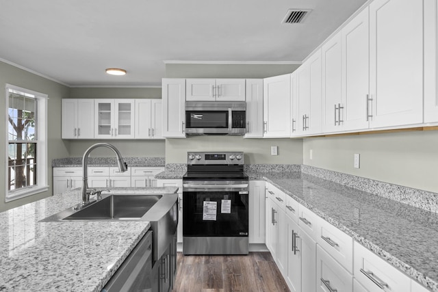 kitchen with white cabinets, appliances with stainless steel finishes, light stone countertops, and ornamental molding