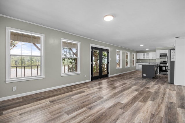 unfurnished living room featuring french doors, hardwood / wood-style flooring, and crown molding