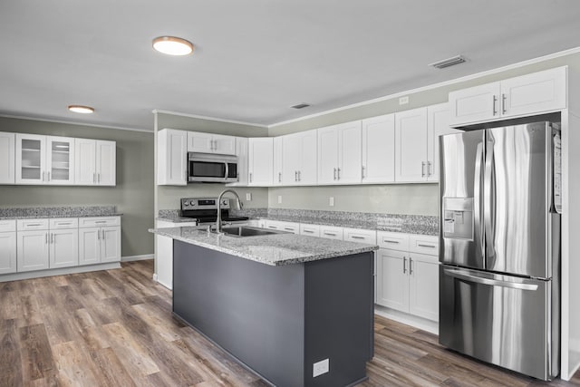 kitchen with an island with sink, sink, white cabinets, and stainless steel appliances