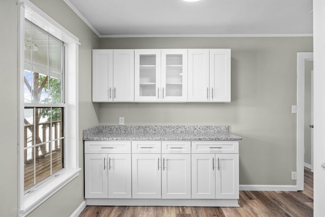 bar featuring light stone countertops, hardwood / wood-style floors, white cabinetry, and ornamental molding