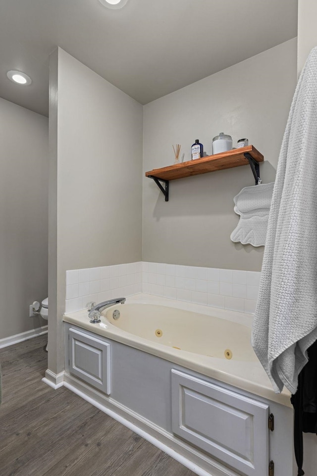  - bathroom featuring wood finished floors, a jetted tub, toilet, and baseboards