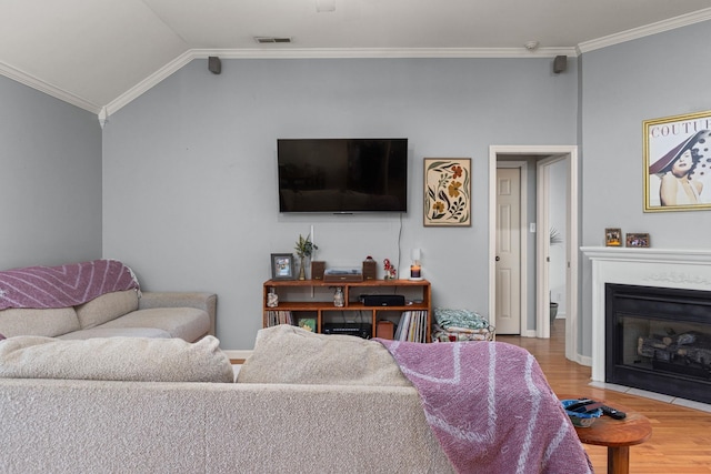  - living area featuring light wood-style flooring, crown molding, vaulted ceiling, a fireplace with flush hearth, and baseboards