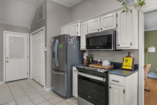  - kitchen with stainless steel appliances, crown molding, dark countertops, white cabinets, and light tile patterned flooring