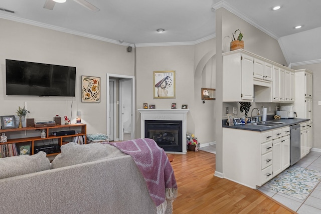  - living area with crown molding, a fireplace with flush hearth, baseboards, arched walkways, and light wood finished floors