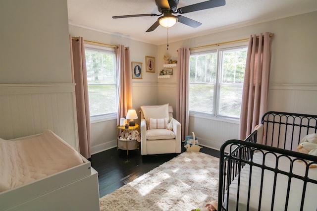  - bedroom with a wainscoted wall, wood finished floors, multiple windows, and a ceiling fan