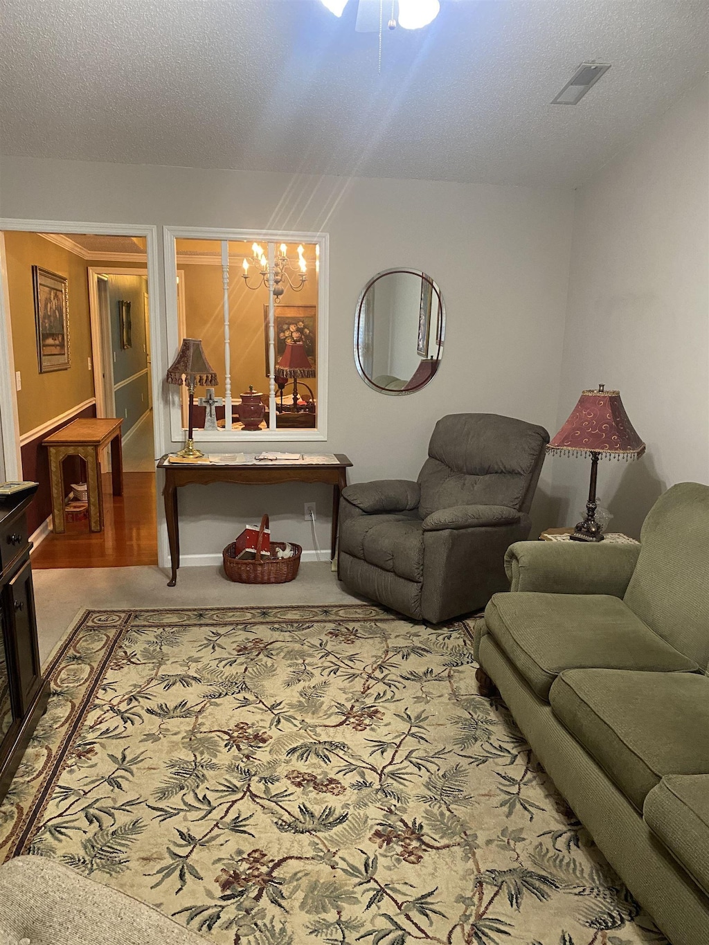living room with a textured ceiling, carpet, a ceiling fan, and visible vents