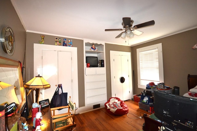 game room featuring hardwood / wood-style flooring, ceiling fan, and crown molding