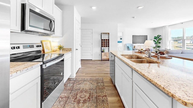  - kitchen featuring stainless steel appliances, a sink, light wood-style floors, white cabinets, and recessed lighting