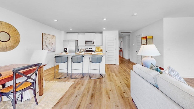  - kitchen featuring appliances with stainless steel finishes, light wood finished floors, white cabinets, recessed lighting, and light countertops