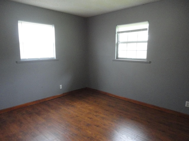  - empty room featuring plenty of natural light, wood finished floors, and baseboards