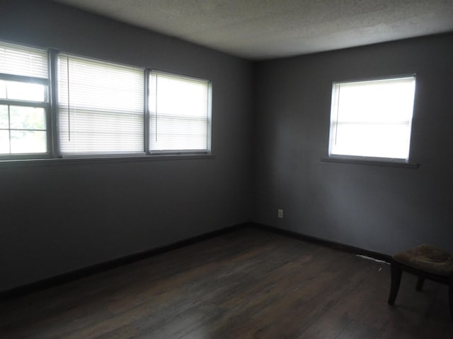  - empty room featuring plenty of natural light, dark wood-style floors, a textured ceiling, and baseboards