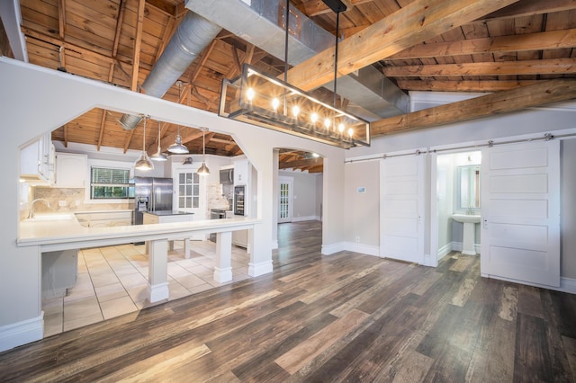 kitchen with white cabinets, decorative light fixtures, a barn door, and wooden ceiling