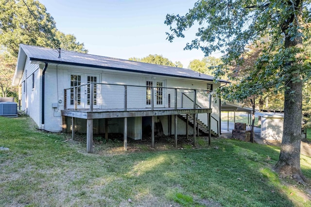 rear view of property featuring central AC unit, a deck, and a lawn