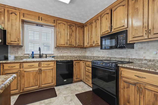 kitchen featuring black appliances, backsplash, light stone counters, and sink