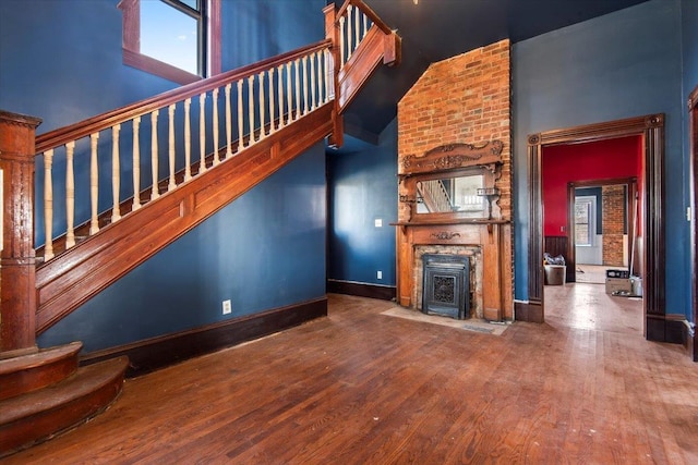 unfurnished living room with hardwood / wood-style floors, a towering ceiling, and a fireplace