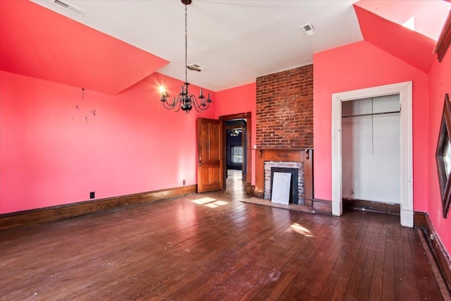 unfurnished living room with an inviting chandelier, dark wood-type flooring, and a fireplace