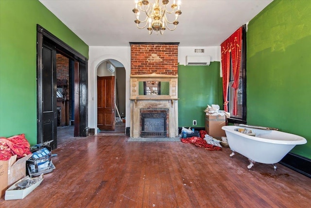 unfurnished living room featuring dark hardwood / wood-style floors, a wall unit AC, a notable chandelier, and a fireplace