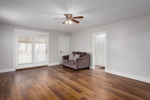 living area featuring ceiling fan, dark hardwood / wood-style floors, and a textured ceiling