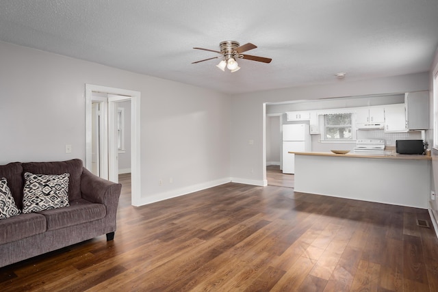 living room with dark wood-type flooring, ceiling fan, and a textured ceiling