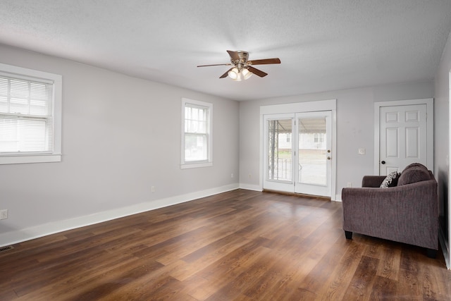 living room featuring ceiling fan, a textured ceiling, and dark hardwood / wood-style flooring