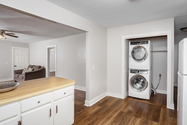 laundry area featuring dark wood-type flooring, stacked washer and dryer, ceiling fan, and a textured ceiling