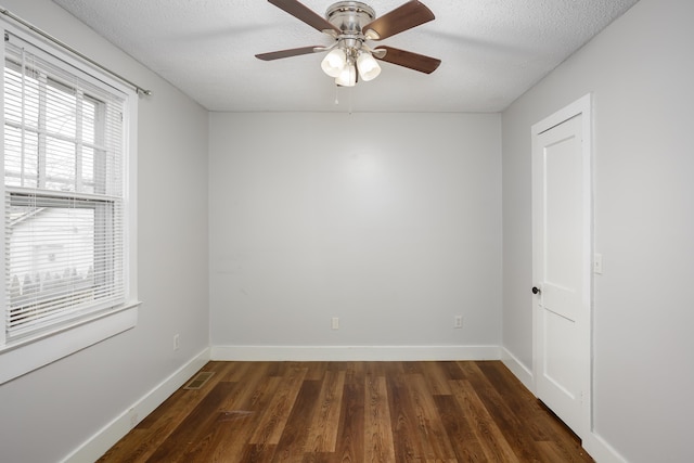 spare room featuring dark wood-type flooring, ceiling fan, and a textured ceiling