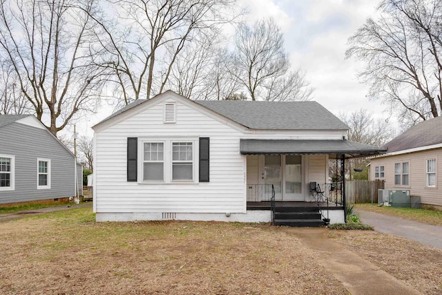 bungalow with cooling unit, a porch, and a front lawn