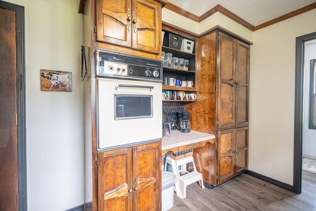  - kitchen with white oven, dark wood-style flooring, crown molding, brown cabinetry, and open shelves