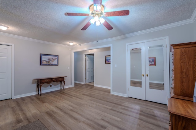 empty room featuring ornamental molding, a textured ceiling, light hardwood / wood-style floors, and french doors