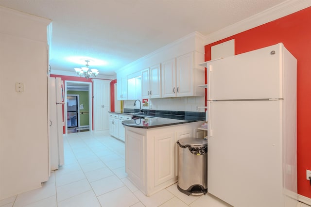 kitchen featuring sink, white cabinetry, crown molding, a chandelier, and white fridge