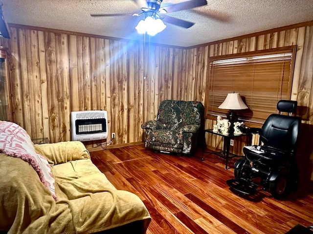 living room featuring hardwood / wood-style floors, wood walls, a textured ceiling, and heating unit