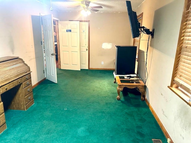 miscellaneous room featuring dark colored carpet, ceiling fan, and a textured ceiling