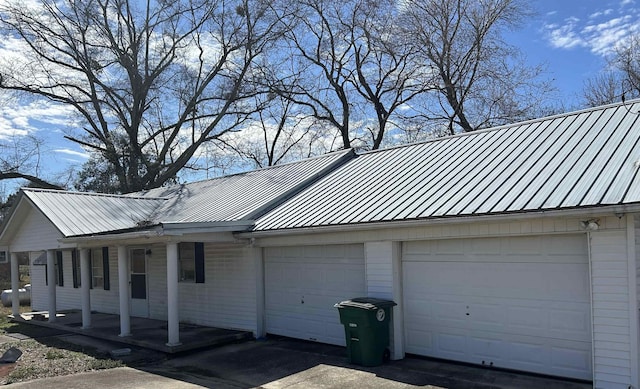 view of property exterior featuring an attached garage, a standing seam roof, and metal roof