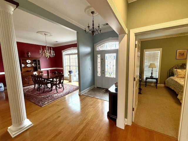 entrance foyer with hardwood / wood-style floors, ornamental molding, decorative columns, and a chandelier