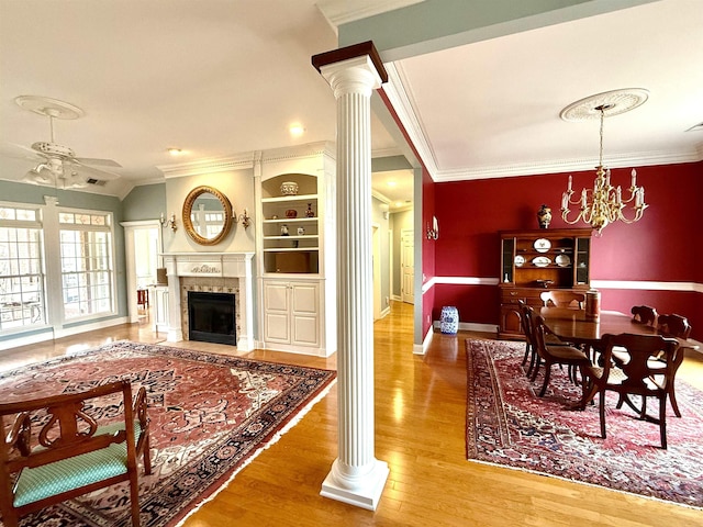 living room with crown molding, hardwood / wood-style floors, ceiling fan with notable chandelier, and ornate columns